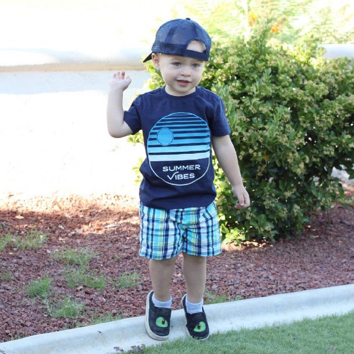 Niño mini fashionista con bermidas, camisa azul y gorra 