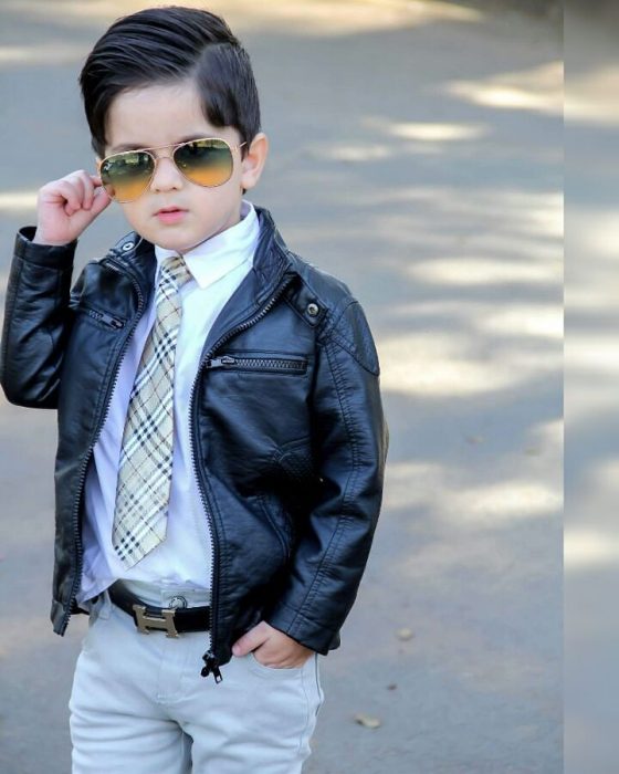 Niño mini fashionista usando chamarra de piel, camisa de vestir y corbata 