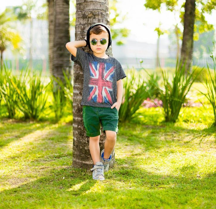 Niño minifashionista usando bermodas verdes y camisa gris con converse gris