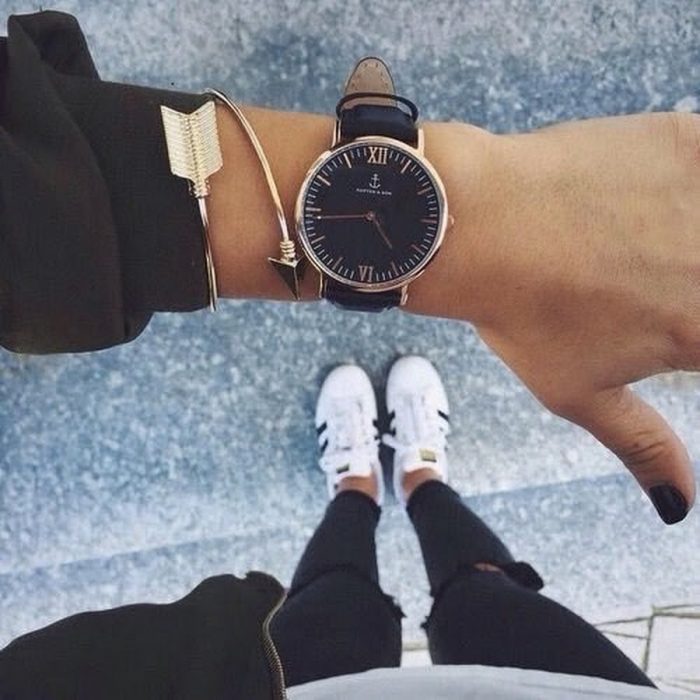 mano de mujer con reloj y pies con tenis 