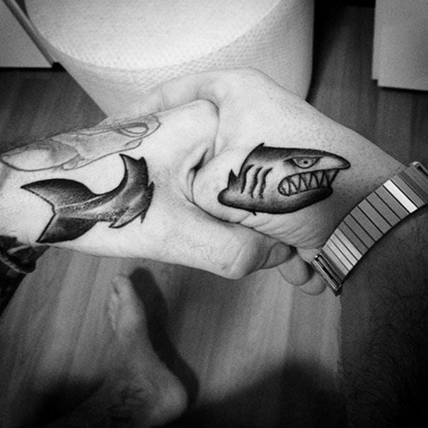 Chico uniendo sus manos para mostrar su tatuaje en forma de tiburón 