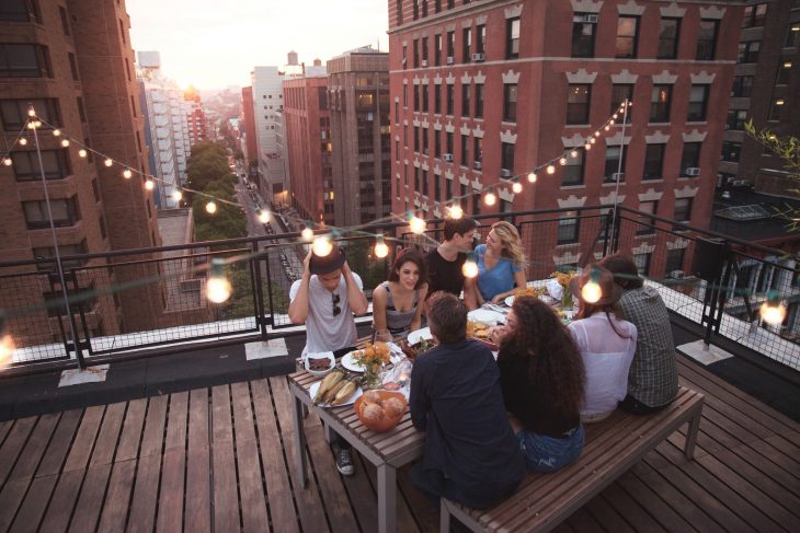 Chicos y chicas comiendo la cena sobre una terraza 