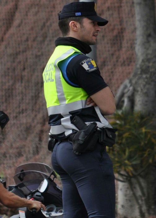 hombre policia de espalda con chaleco fosforecente 