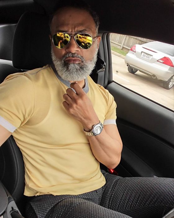 hombre moreno con músculos y barba sentado en coche 