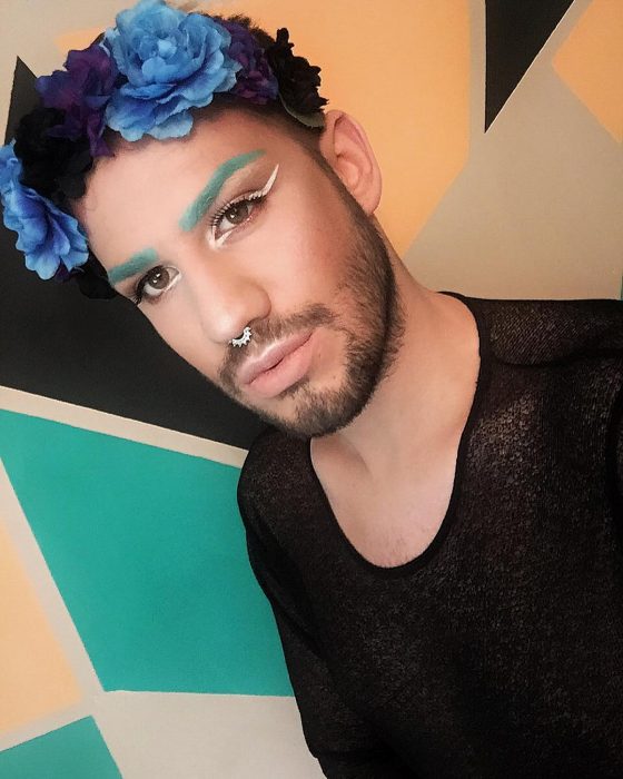 hombre con cejas azules, maquillaje y barba 