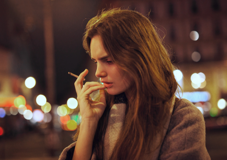 Chica fumando mientras está parada en medio de la calle fumando 