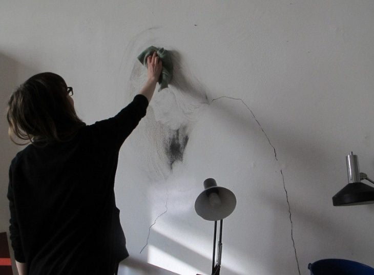Chica limpiando una pared con un dibujo
