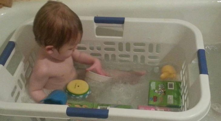 Niño dentro de una caja de pastico que está adentro de una bañera 