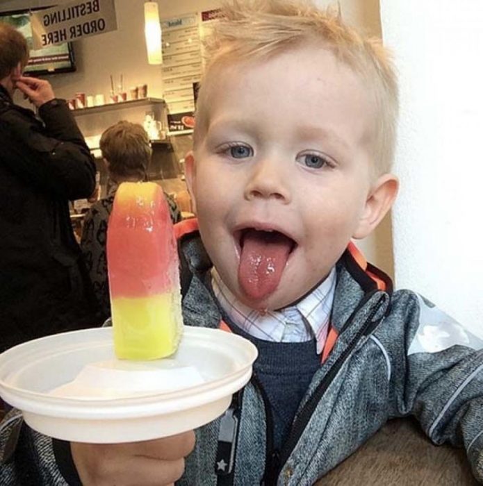 Niño comiendo una paleta helada colocada sobre una tapadera de café para evitar derrames 