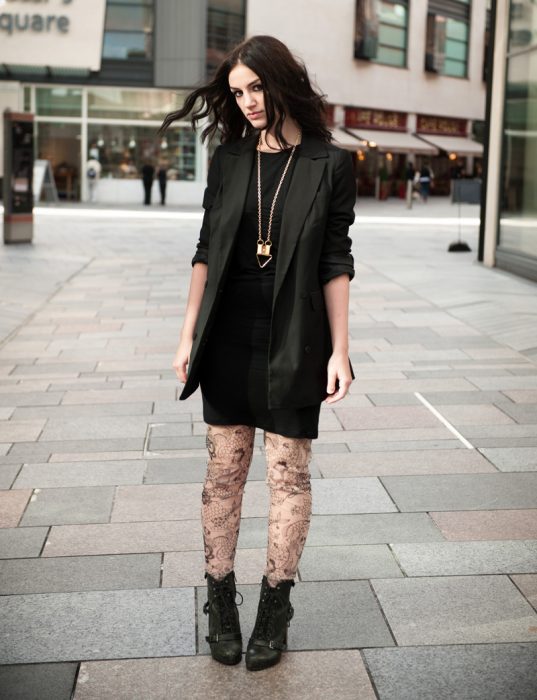 chica con vestido y saco negros, medias de encaje