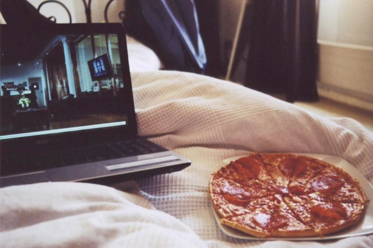 pizza y computadora en cama