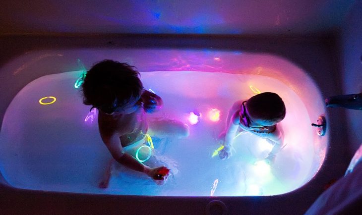 bebés en tina de baño con barritas fluorescentes de colores