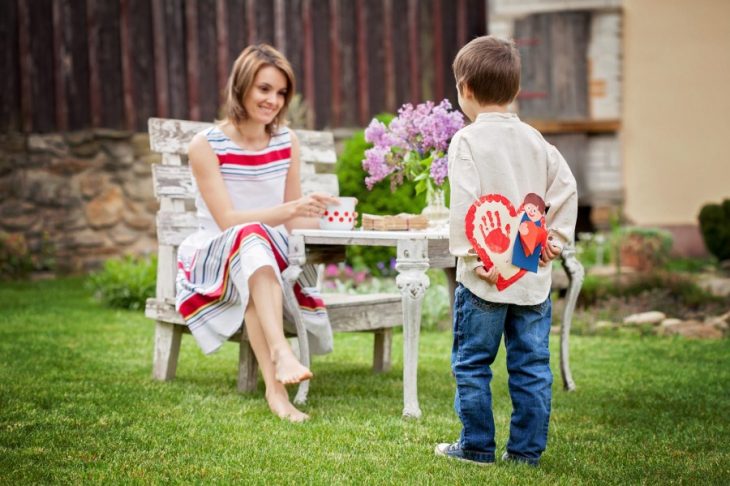 niño pequeño dando regalo a su mamá