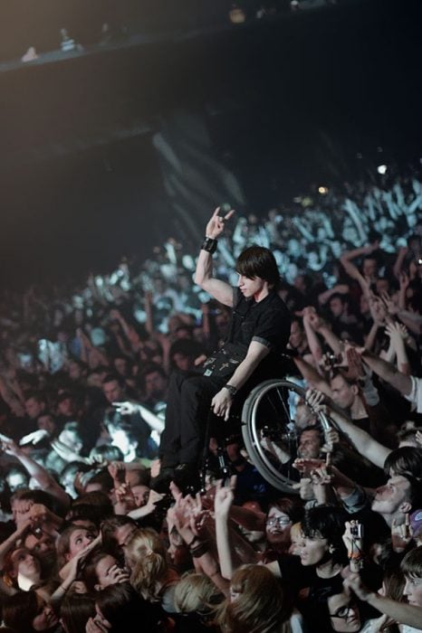 chico en silla de ruedas levantado por la multitud en concierto