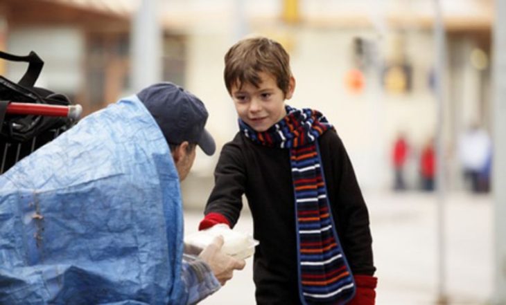 niño da comida a un hombre sin hogar