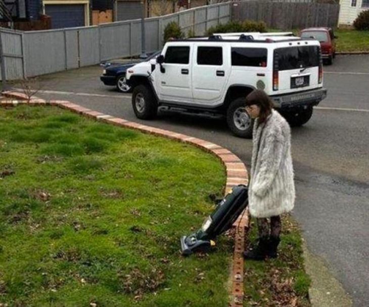 mujer tratando de aspirar césped