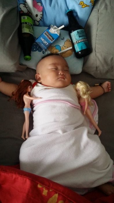 bebé rodeado de botellas y muñecas