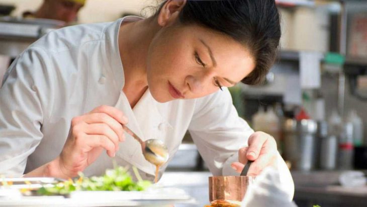 mujer de cabello negro cocina y decora plato 