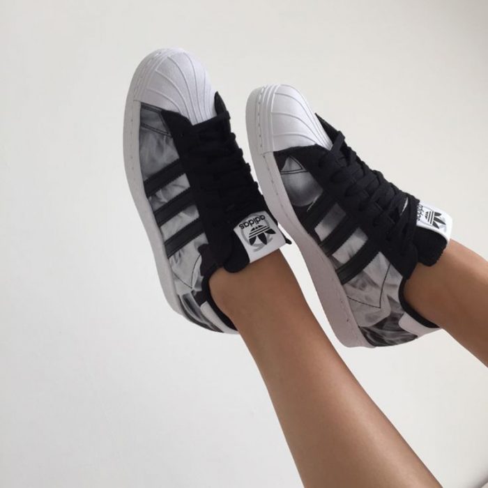 pies de mujer con tenis adidas superstar negro 