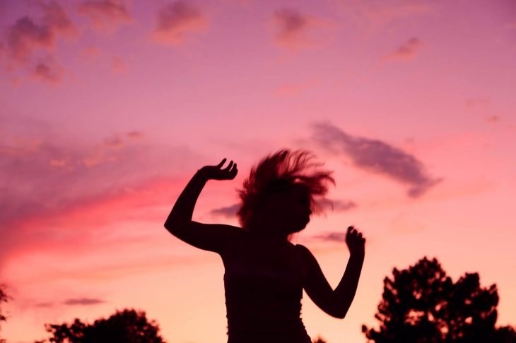 mujer saltando y cielo de atardecer rosa 