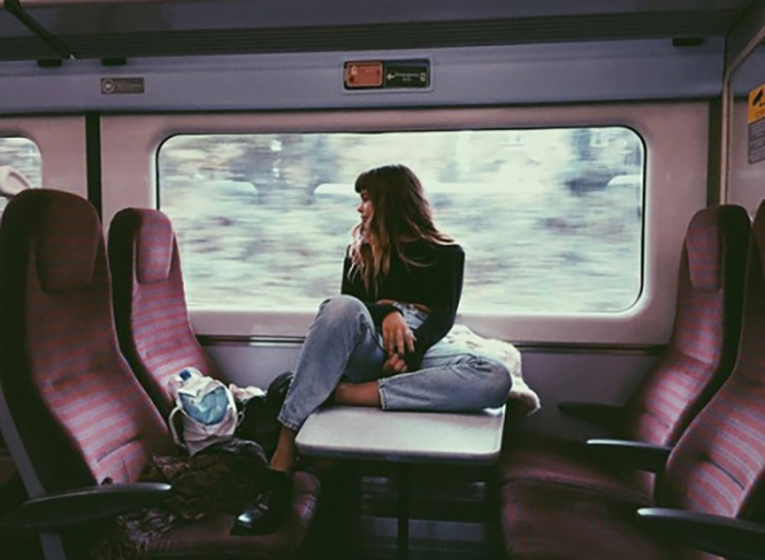 Joven sentada en la mesa central de un tren. 