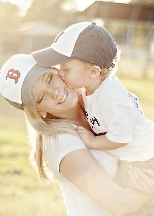 Niño besando a su madre en la mejilla mientras ella lo sostiene 