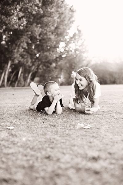 Chica sentada en el pasto junto a su hijo pequeño 