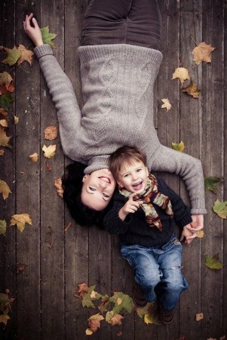 Mujer recostada en el suelo junto a su pequeño hijo 