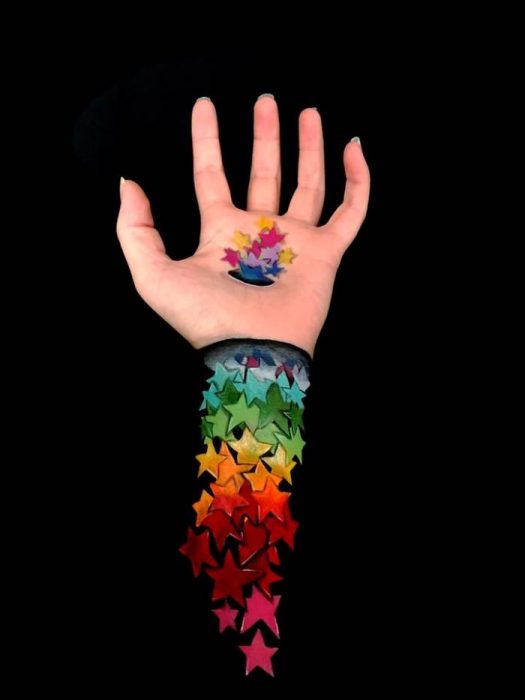 Chica que crea ilusiones ópticas en su mano, con estrellas dibujadas en su brazo 