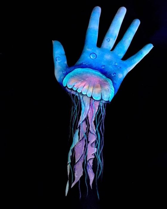 Chica que crea ilusiones ópticas en su mano, con una medusa sobre su mano 