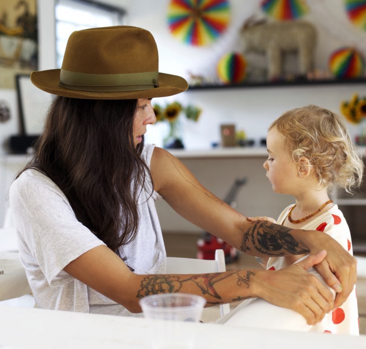 Chica con tatuajes cuidando un bebé 