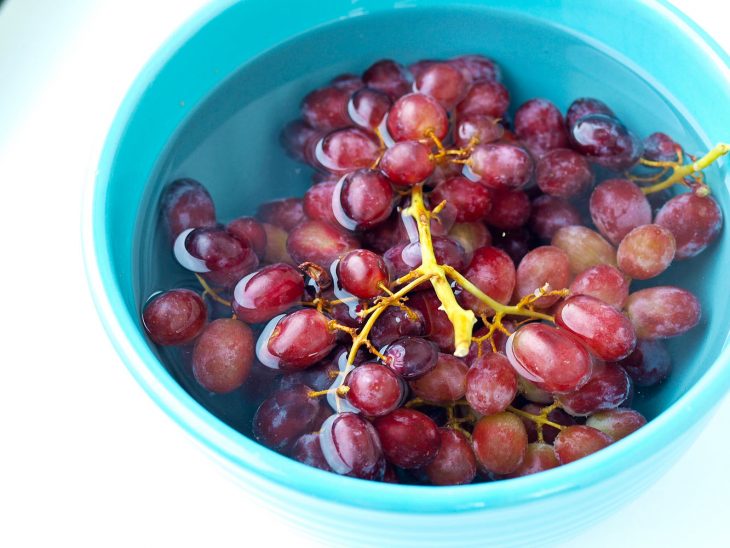 Uvas dentro de un recipiente con agua caliente para rehidratarlas 