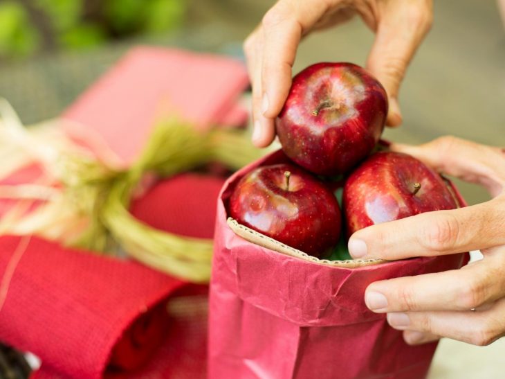 Manzanas rojas dentro de una bolsa de papel color rojo