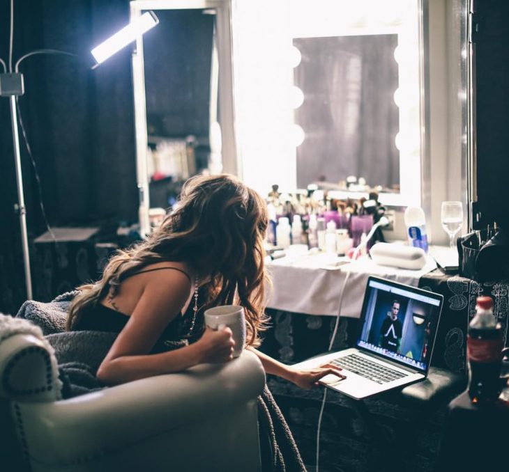 Chica con una taza de café en la mano y viendo su computadora 