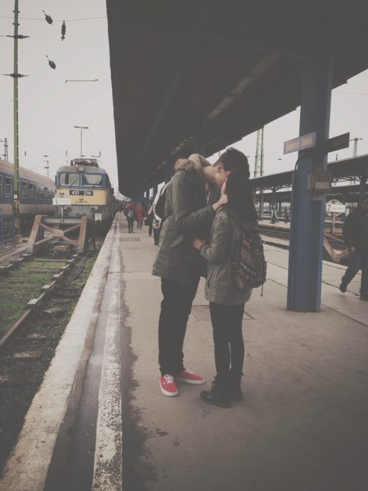 Pareja besándose en un anden de tren 