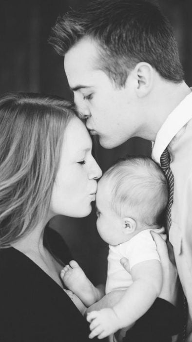 Hombre besando a su esposa mientras ella besa a su bebé 