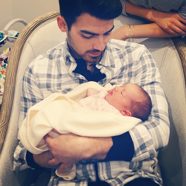 Joe Jonas cargando a su bebé en brazos y viéndolo 