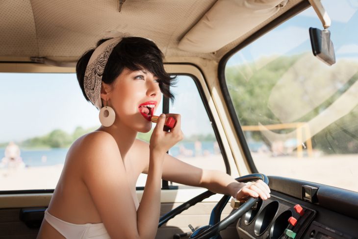 mujer de cabello corto maquillándose en el coche 