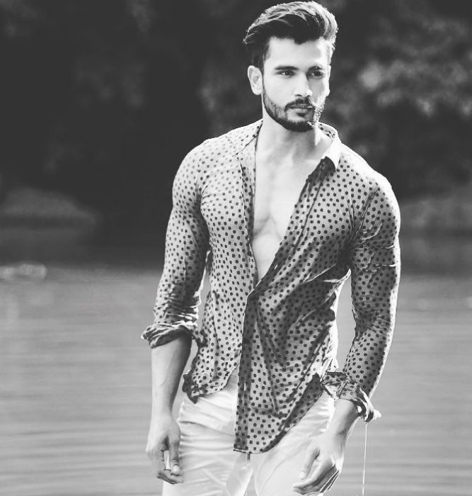 Rohit Khandelwal nuevo Mr. World parado dentro de un lago posando para una sesión de fotos 