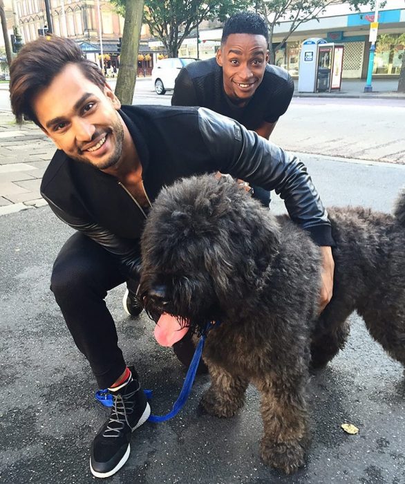 Rohit Khandelwal de la India ganador del concurso Mr. World 2016 abrazando a un perrito en color negro 