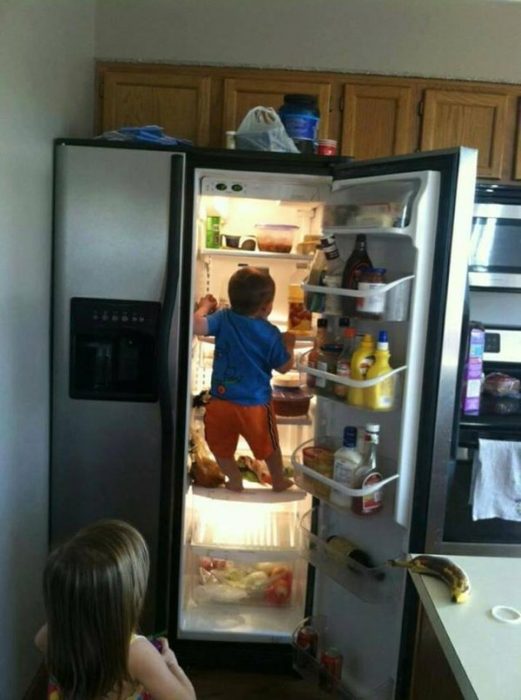 Niño escalando por el refrigerador 