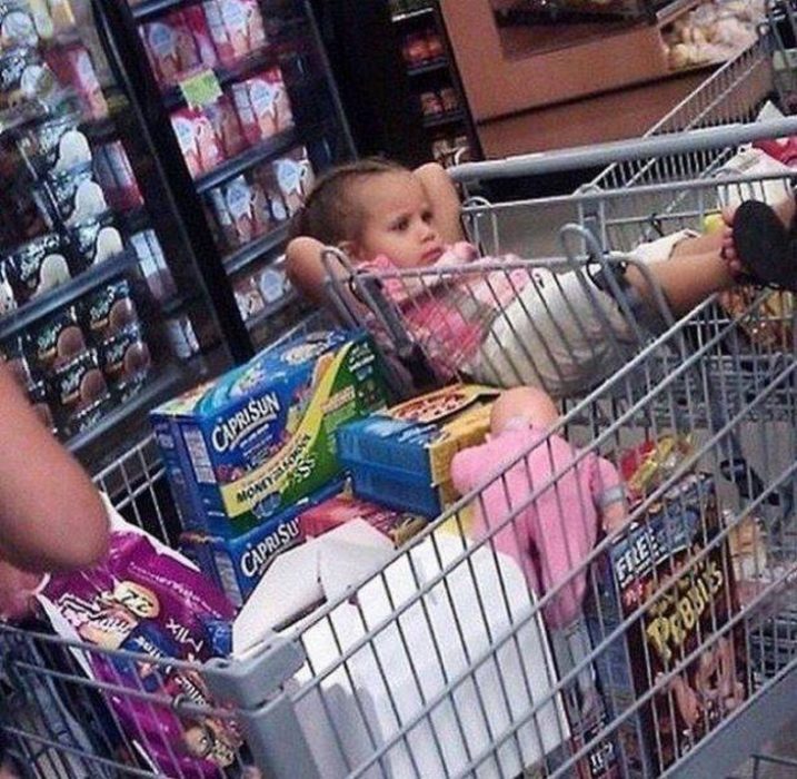 Niña recostada en el carrito del supermercado 