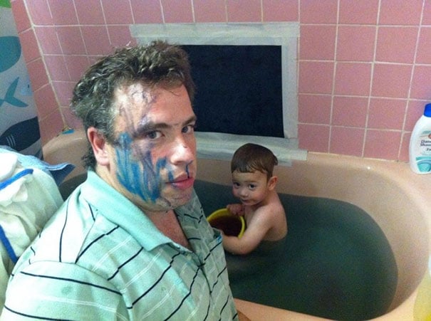 Papá bañando a su hijo que está lleno de pintura de marcador