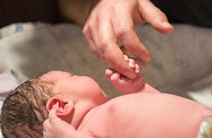 bebé recién nacido tomando del dedo a papá