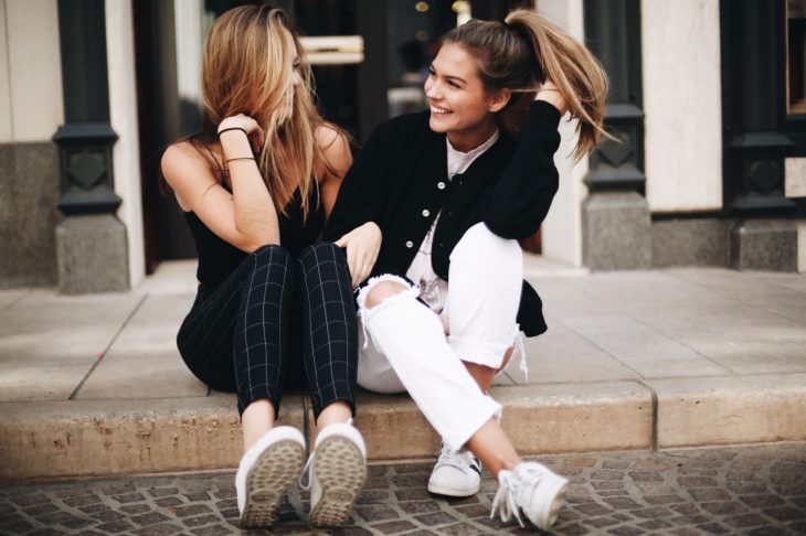 Chicas sentadas en una banqueta conversando y riendo