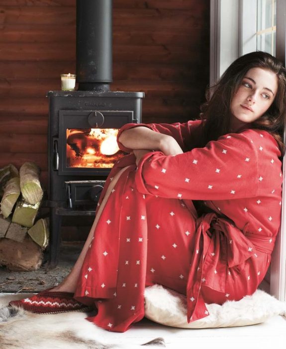 mujer con pijama roja sentada junto a la ventana pensando 