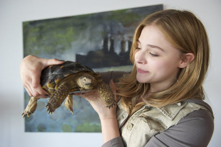 mujer rubia con tortuga en la mano 