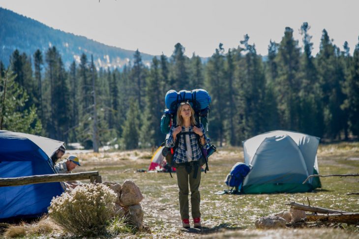 mujer rubia con mochila en el bosque 