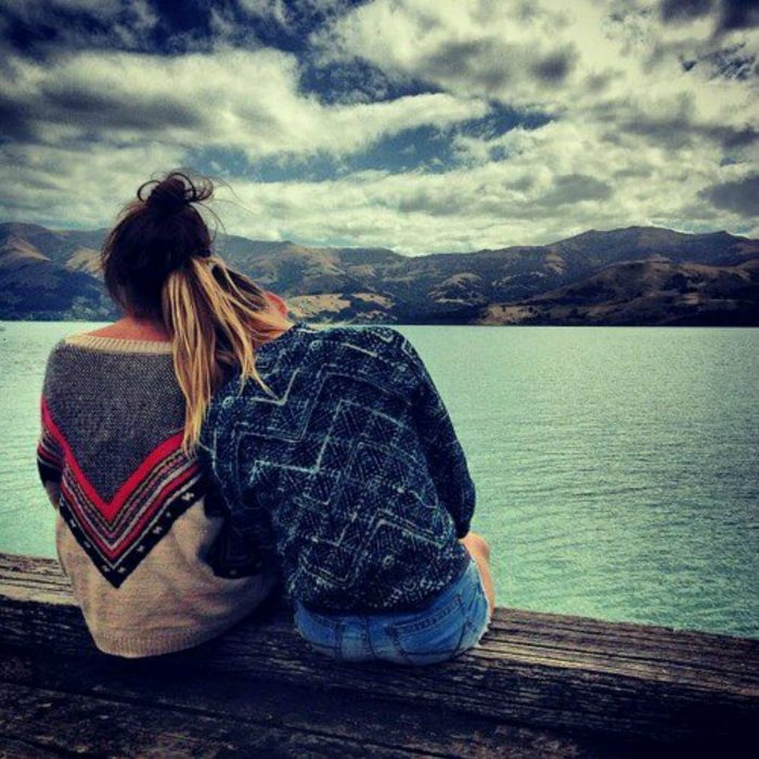 Amigas sentadas en la orilla de un lago 