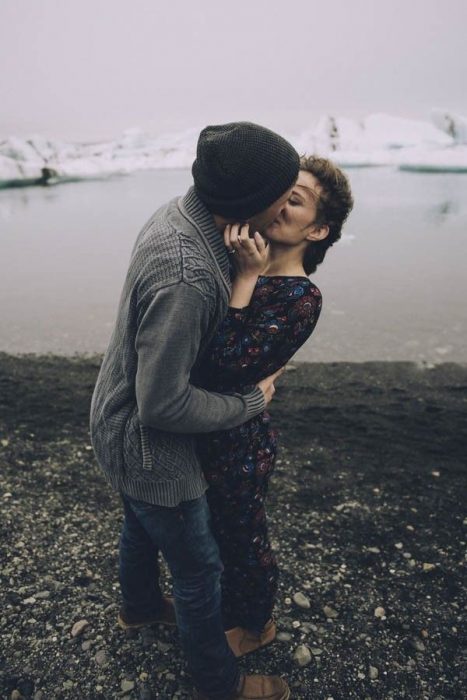 Pareja besándose frente a un lago 